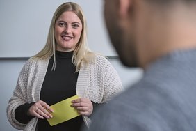 Freundliche Frau mit Karte in der Hand - Mann verschwommen von hinten im Vordergrund